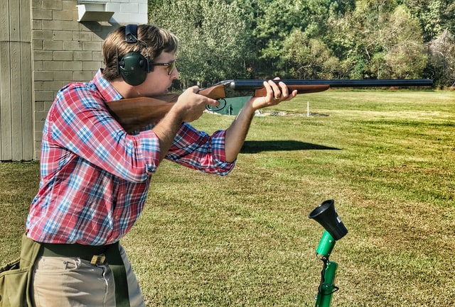 A person wearing proper shooting gear, aiming at their target
