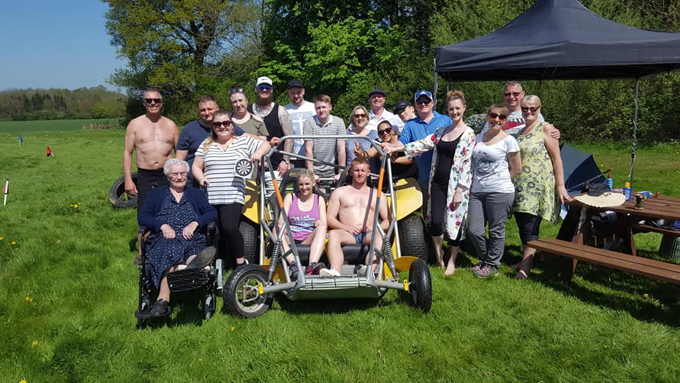 A group of people posing with a power turn buggy