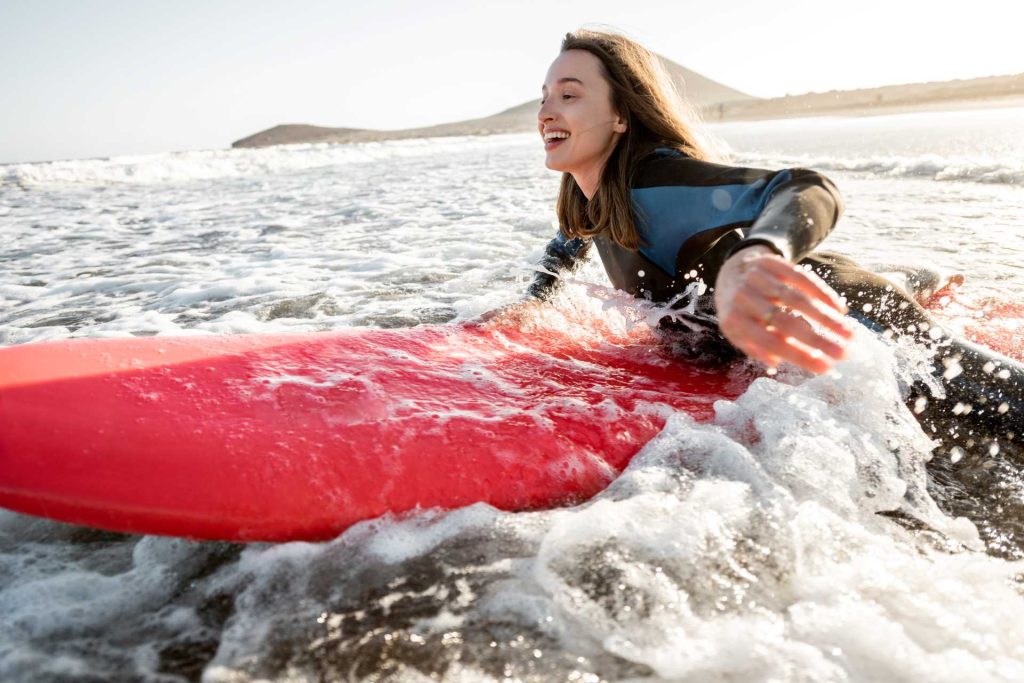 new sports to try, woman on surfboard