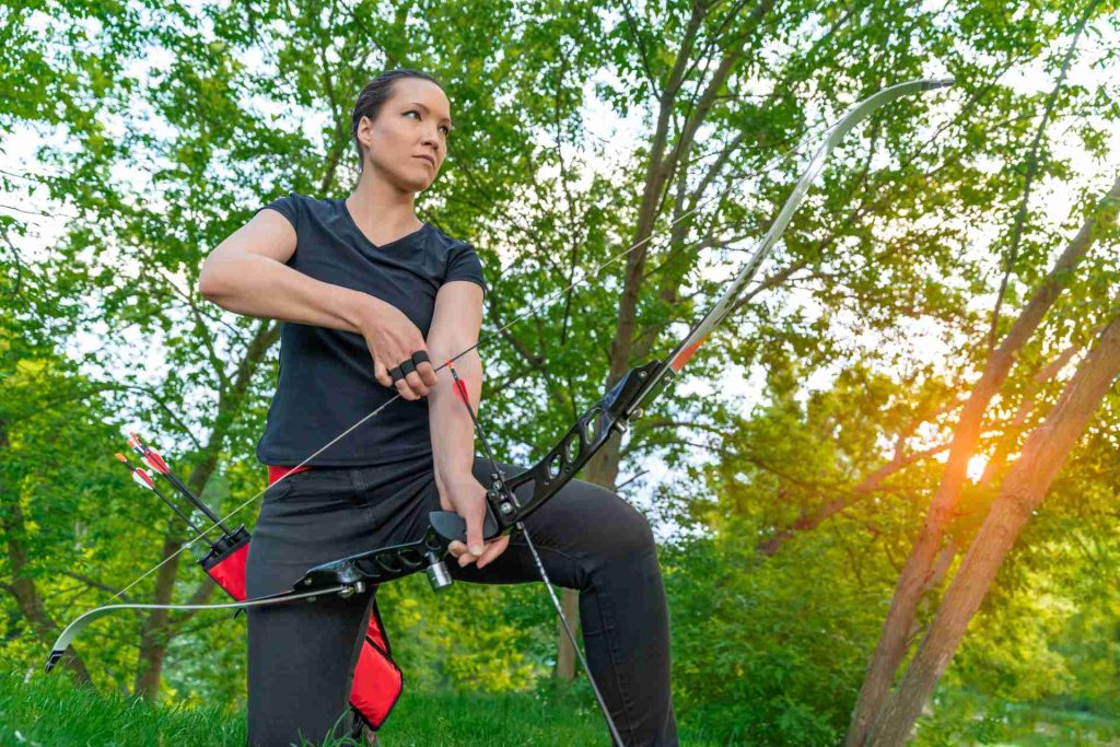 sports that need strength, woman with bow and arrow outdoors