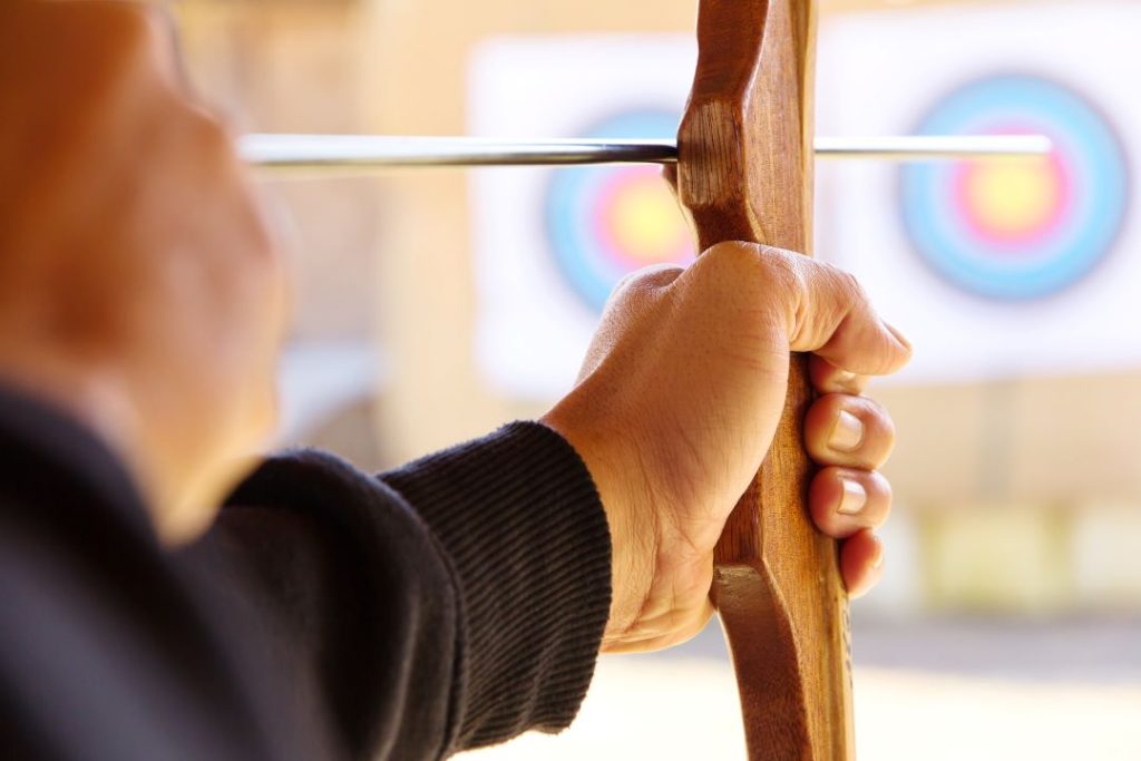 activities for stag do, a close up shot of a person holding their bow and aiming at a target