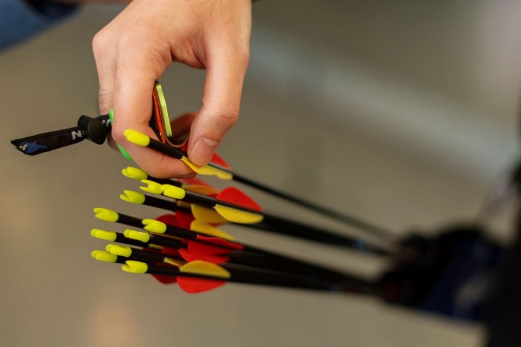 benefits of blindfold archery for focus, a close-up shot of a hand holding vibrant arrows