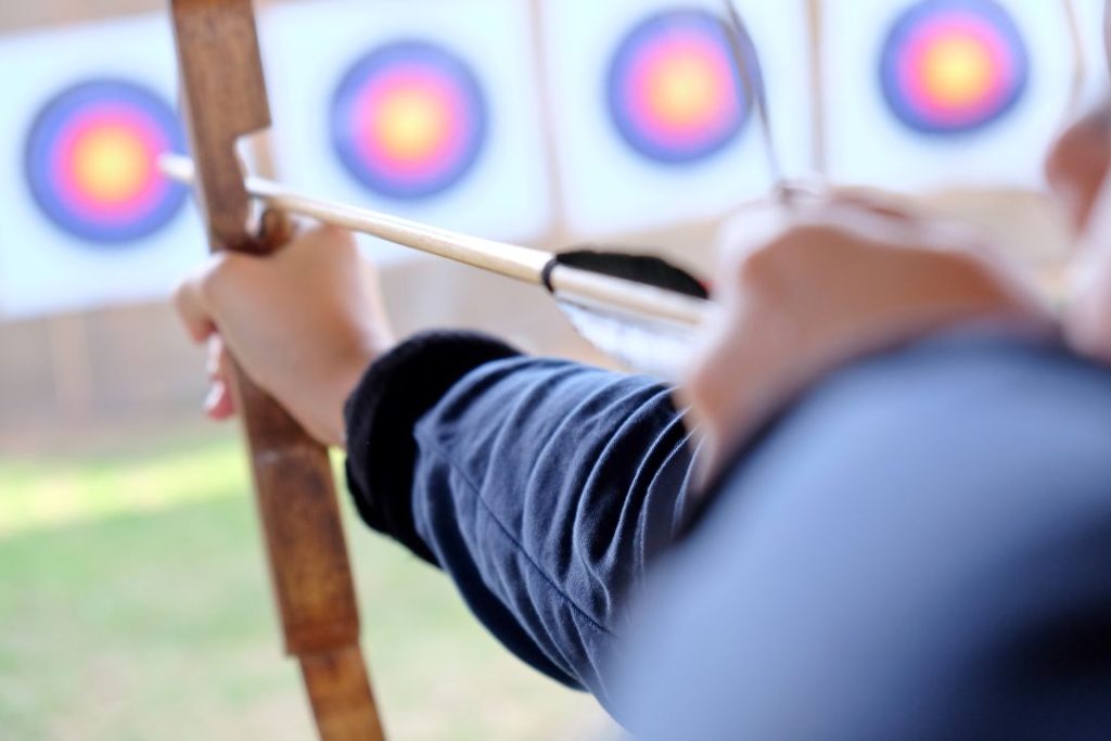 how blindfolded archery improves focus, a close-up shot of a person holding their bow aimed at a target