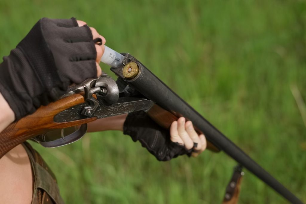 clay pigeon shooting for children tips, close up of a person loading shells into a double-barreled shotgun 