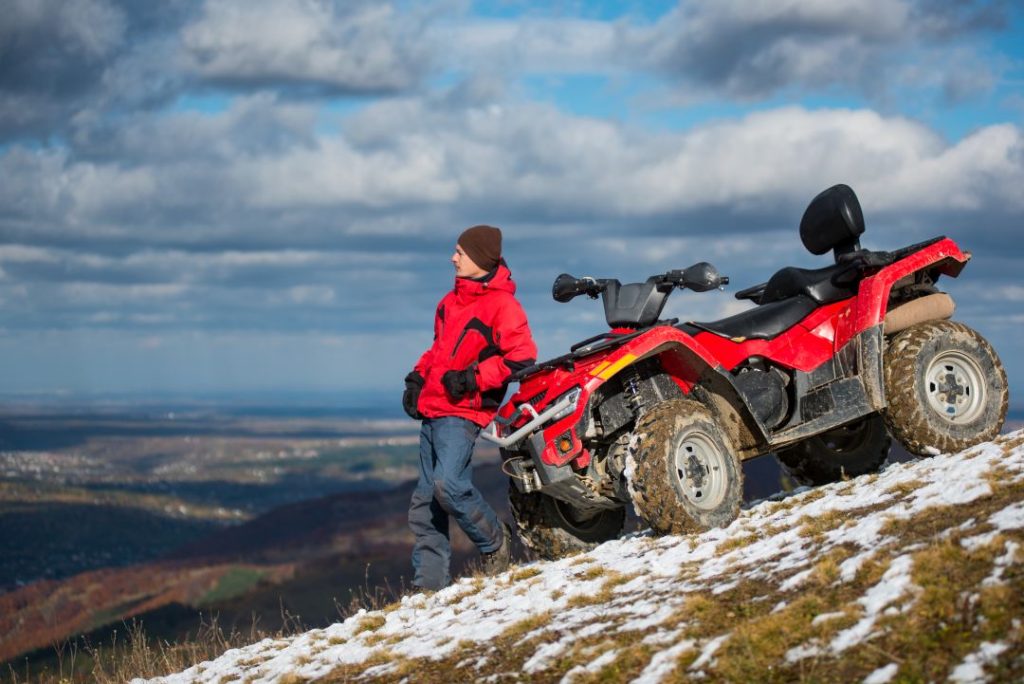 holiday activity voucher, a man with a red quad bike on a snowy mountain top