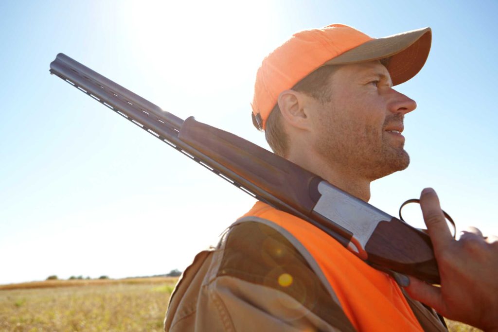 a man hauling a shot gun on his shoulder 