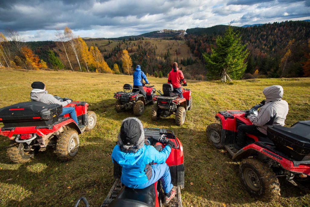 inclusive team events, Group of people riding a off-road vehicles on hill.
