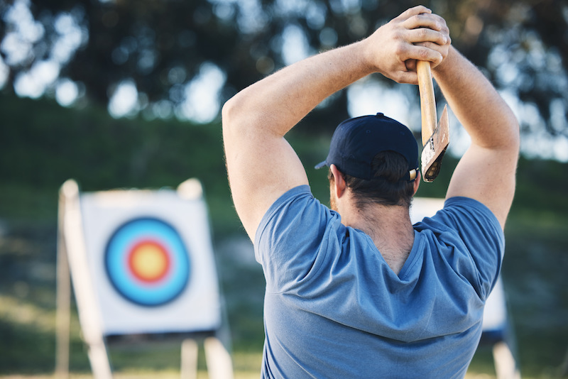 Skills gained from adventure sports, a man throwing an axe at a target.