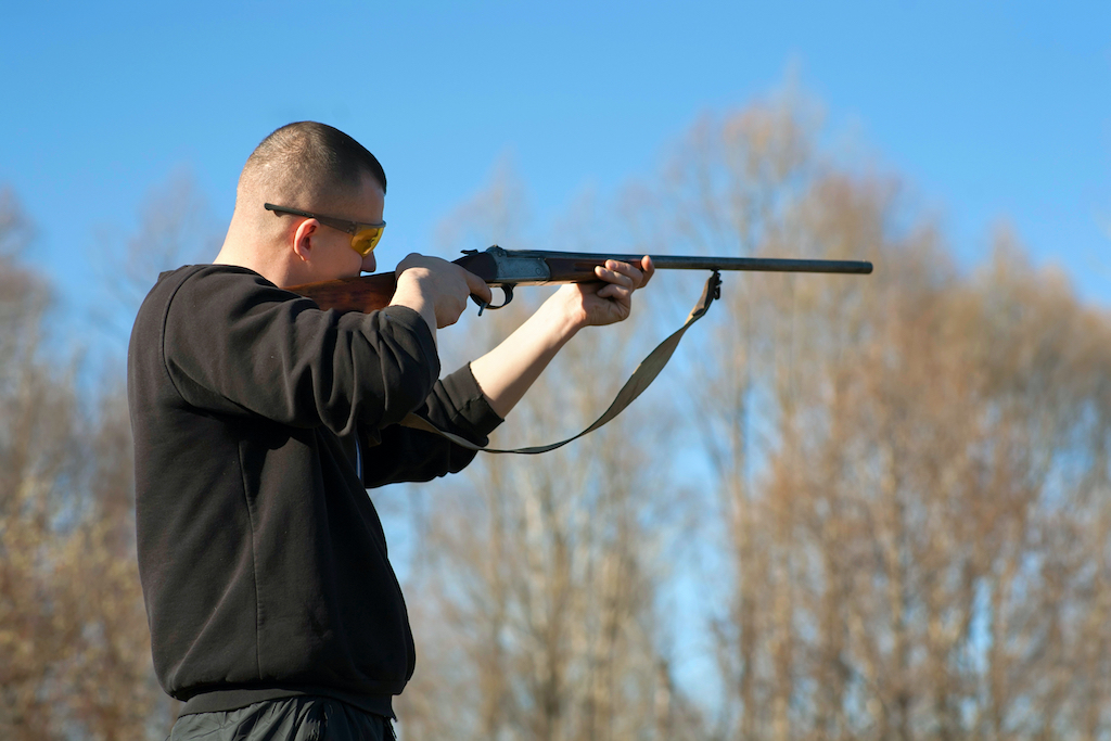 First time clay pigeon shooting, man wearing protective gear using shotgun.