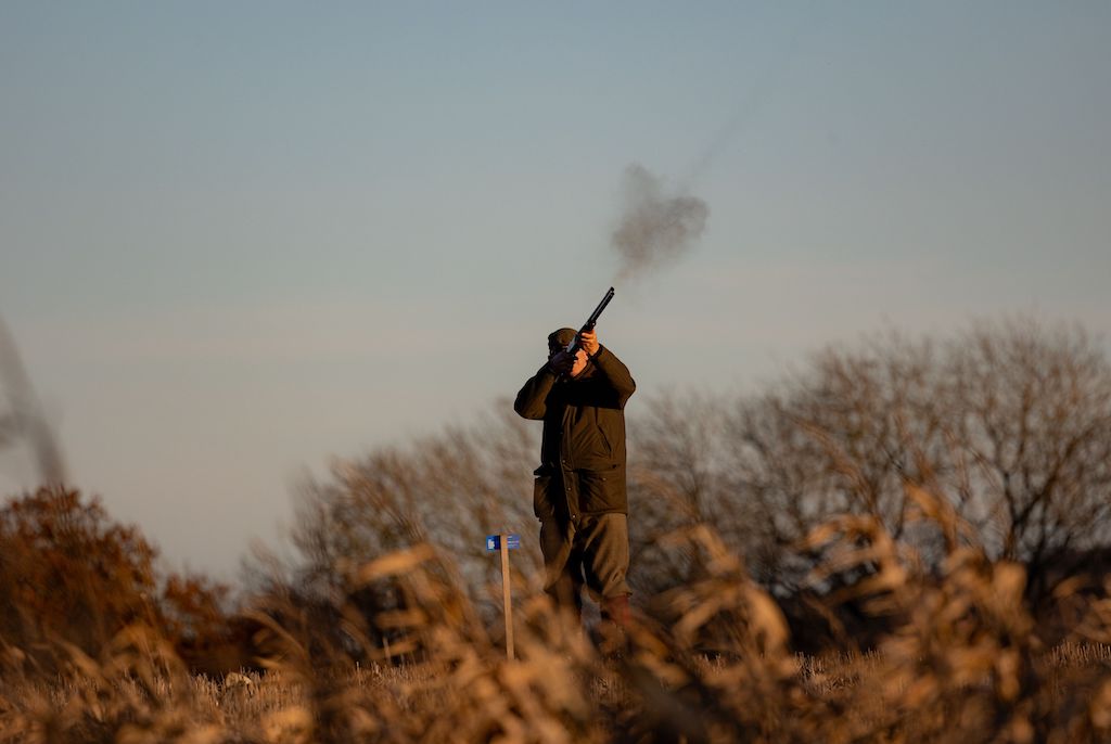 First time clay pigeon shooting, man shooting target in the air.
